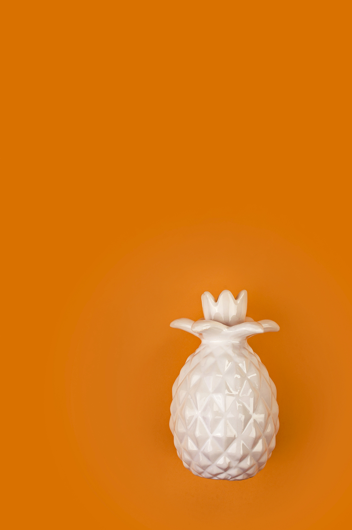 装饰陶瓷白色菠萝在明亮的橙色背景。橙色背景上的菠萝，流行的颜色